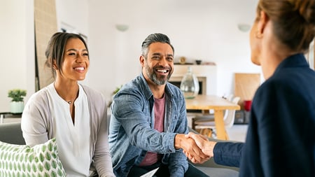a man with his partner shaking hands with a business women. 