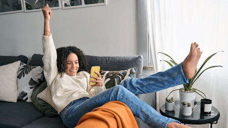 a women with her fist in the air while looking at her smart phone. 
