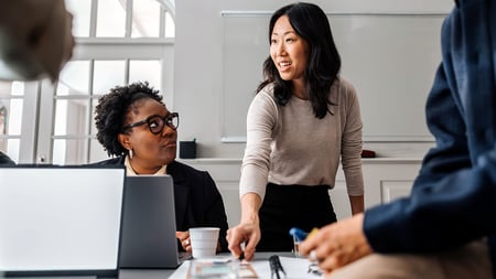 A women setting a paper down on a table while conducting a meeting. 