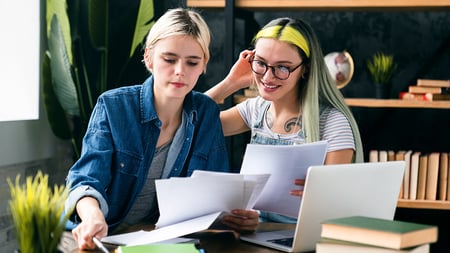 A pair of young women looking over a pile of paperwork