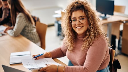 a smiling student working on a paper