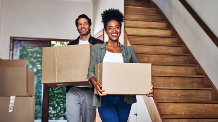 a young couple moving boxes into a home. 